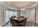 Elegant dining room with tray ceilings, modern chandelier, natural light and a large wood table with seating for eight at 1692 Branch Creek Cv, Lawrenceville, GA 30043