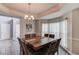 Well-lit dining area featuring a wooden table with seating for eight, tray ceilings, and decor that creates an inviting atmosphere at 1692 Branch Creek Cv, Lawrenceville, GA 30043