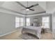 Main bedroom featuring a tray ceiling, ceiling fan, plush carpet, and bright windows at 1692 Branch Creek Cv, Lawrenceville, GA 30043