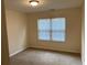 Well-lit bedroom featuring a large window with blinds and neutral carpeting at 7981 Gossamer Dr, Fairburn, GA 30213