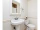 Bright bathroom featuring a pedestal sink, toilet, and decorative wainscoting at 1167 Mcclung Rd, Hiram, GA 30141