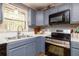 Compact kitchen showcasing blue cabinets, stainless steel oven, and double sink under a bright window at 1167 Mcclung Rd, Hiram, GA 30141