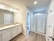 Bathroom featuring double sinks, granite counters, and a glass-enclosed shower with wood-look floors at 5547 Bent Grass Way, Douglasville, GA 30135