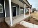 Inviting front porch with white columns, brick accents, and a dark gray door at 5547 Bent Grass Way, Douglasville, GA 30135