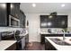 Modern kitchen with dark cabinetry, stainless steel appliances, and quartz countertops at 7711 Cabrini Pl, Fairburn, GA 30213