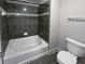 Bathroom with bathtub, toilet and dark gray tiled walls at 1206 Persimmon Way, Mcdonough, GA 30252