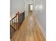 Well-lit hallway with hardwood floors and decorative staircase, offering seamless transition between rooms at 340 Town Center Ave # 215, Suwanee, GA 30024