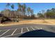 View of community tennis and basketball courts, surrounded by trees, and illuminated by street lights at 132 Oliver Dr, Locust Grove, GA 30248