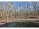 Wooded backyard with gravel driveway and grassy area at 1422 Hillside Dr, Grayson, GA 30017