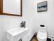 Compact bathroom featuring a wall-mounted sink with a modern faucet, a toilet, and stylish fixtures against white walls at 1822 Avon Sw Ave, Atlanta, GA 30311