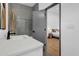 Bathroom featuring gray subway tile in shower and doorway view into bedroom with wood floors at 1822 Avon Sw Ave, Atlanta, GA 30311