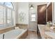 Relaxing bathroom with garden tub, neutral tile, and plantation shutters at 2085 Melrose Trce, Cumming, GA 30041