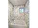 Renovated bathroom showcasing elegant marble-patterned tile walls and a clean, bright bathtub/shower combination at 3278 Abbeywood Dr, Decatur, GA 30034