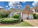 Brick house exterior with two-car garage and landscaping at 1305 Leisure Lake Dr, Lawrenceville, GA 30044