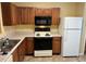 Galley kitchen with wood cabinets, and white appliances at 2087 Grove Way, Hampton, GA 30228