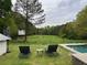 Spacious backyard featuring a pool, lounge chairs, and a treehouse overlooking a lush green field at 10975 Hutcheson Ferry Rd, Chattahoochee Hills, GA 30268