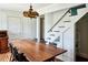 Dining room with a large wooden table, vintage chandelier, and staircase in background at 10975 Hutcheson Ferry Rd, Chattahoochee Hills, GA 30268