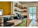Charming kitchen corner with open shelving, a white ceramic sink, green cabinets and black countertops at 10975 Hutcheson Ferry Rd, Chattahoochee Hills, GA 30268