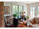 Bright living room with a wooden desk, cushioned furniture, and large windows providing ample natural light at 10975 Hutcheson Ferry Rd, Chattahoochee Hills, GA 30268
