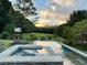 Outdoor in-ground pool and spa are surrounded by lush greenery and trees in a serene setting at 10975 Hutcheson Ferry Rd, Chattahoochee Hills, GA 30268