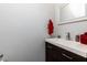 Simple bathroom with dark vanity, white sink, and red accents at 3812 Stonewall Se Ter, Atlanta, GA 30339