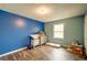 Spacious bedroom with laminate wood flooring, a dresser, and large blue accent wall at 1987 Allwood Ct, Lawrenceville, GA 30044