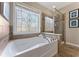 Main bathroom featuring tile floors, decorative window, and large soaking tub at 702 Berkeley Ter, Canton, GA 30115