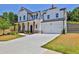 Two-story white farmhouse with gray stone accents, a large driveway, and landscaping at 399 Tillman Pass, Woodstock, GA 30188