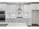 White kitchen cabinets, quartz countertops and a stainless steel range hood at 1682 Juniper Berry Way, Loganville, GA 30052