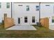 Backyard showcasing a concrete patio, grassy lawn, and a white home exterior with black trim and a wooden fence at 883 Eagle Ave, Riverdale, GA 30296