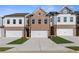 Three-story townhouses with brick and white siding, two-car garages, and landscaping at 883 Eagle Ave, Riverdale, GA 30274