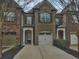 Brick front exterior of townhome with 2-car garage and landscaping at 1710 Garbrooke Cv, Lawrenceville, GA 30046