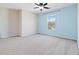 Well-lit bedroom with light blue accent wall and window at 6397 Barker Station Walk, Sugar Hill, GA 30518