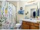 Bright bathroom with a floral shower curtain, warm lighting, and a wooden vanity at 230 Cobblestone Ln, Mcdonough, GA 30252