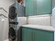 Modern laundry room with stacked washer and dryer, green cabinets, and white tile at 1544 Bullard Rd, Powder Springs, GA 30127