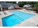 Community pool with lane markers, lounge chairs, tables, umbrellas, and surrounding foliage at 6851 Roswell Rd # J1, Atlanta, GA 30328