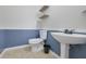 Well-lit half bathroom with pedestal sink, white toilet, floating shelves, tile flooring, and calming two-tone blue walls at 148 Shady View Pl, Lawrenceville, GA 30044