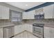 Well-lit kitchen showcases stainless steel appliances, granite countertops, tile backsplash and white cabinets with a modern aesthetic at 148 Shady View Pl, Lawrenceville, GA 30044