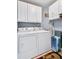 Well-organized laundry room with white cabinets, washer, dryer, ironing board, and a laundry basket at 322 Berkshire Trce, Canton, GA 30115