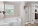 A bathroom featuring a soaking tub with shower and a large window overlooking the backyard at 42 Millstone Gln, Dallas, GA 30157