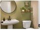 Stylish bathroom with a pedestal sink, green walls, and modern fixtures at 1720 Habersham Villa Dr, Cumming, GA 30041