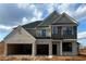 Two-story home with gray and white brick exterior, three-car garage, and new construction at 4064 Hosch Retreat Dr, Buford, GA 30519