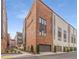 Modern townhome showcasing a brick facade, dark trim, a garage, and beautiful landscaping at 1244 Chelsea Nw Cir, Atlanta, GA 30318