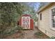 A charming red shed with white trim nestled in a partially wooded backyard adds extra storage at 257 Vance Ne Cir, Marietta, GA 30060