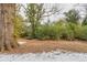 Partially snow-covered backyard with mature trees and landscaping at 1728 W Austin Rd, Decatur, GA 30032