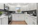 Well-appointed kitchen with white cabinets, black hexagon tile backsplash, and stainless steel appliances at 1626 Rice Rd, Lithonia, GA 30058