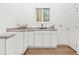 Kitchenette featuring white cabinets, countertops, a stainless steel sink, and a window for natural light at 1626 Rice Rd, Lithonia, GA 30058