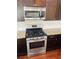 Close up of a stainless oven and microwave surrounded by granite counter tops, and dark cabinets at 1963 White Top Rd., Lawrenceville, GA 30045