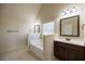 Bathroom featuring a soaking tub with dark wood cabinets and vanity sink at 3535 Clarecastle Dr, Buford, GA 30519