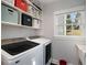 Well-organized laundry room with front-load washer/dryer, storage shelves, and a bright window at 3495 Habersham Nw Rd, Atlanta, GA 30305
